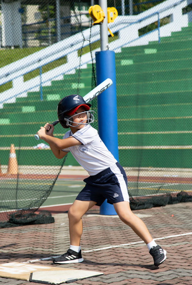 Young boy in uniform and cap holding a bat over his shoulder.